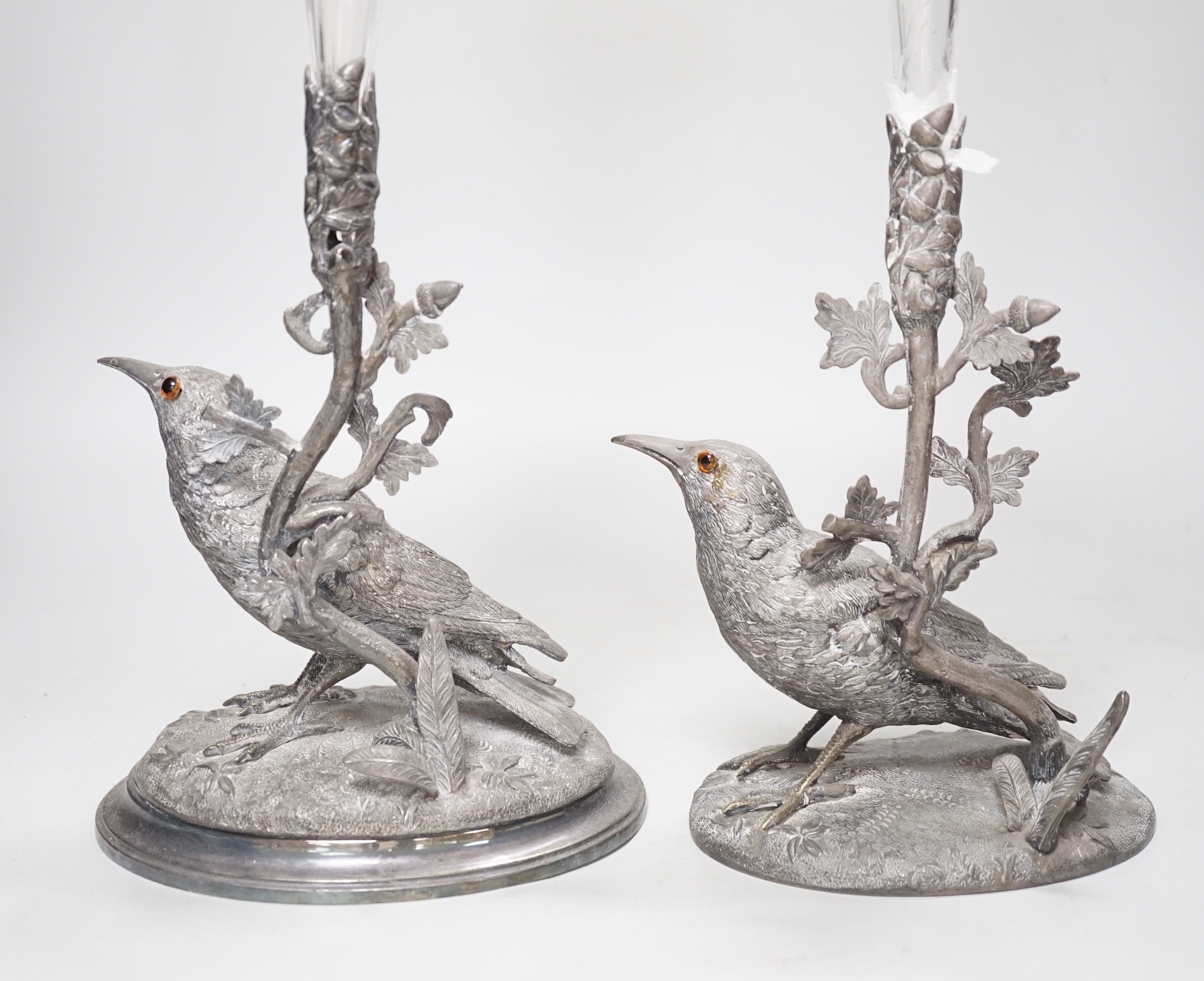 A matched pair of silver plated bird vases, with glass flutes, one with etched decoration, the largest 35cm high